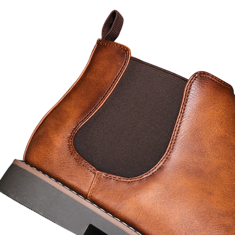 Zbliżenie na Arkadya Outlet Botki męskie wsuwane sztyblety zimowe zamknięta forma z brązowej skóry z ciemnym elastycznym panelem bocznym, widocznymi szwami, zakładką, czarną podeszwą i bez zapięcia, sfotografowane na jasnym tle.
