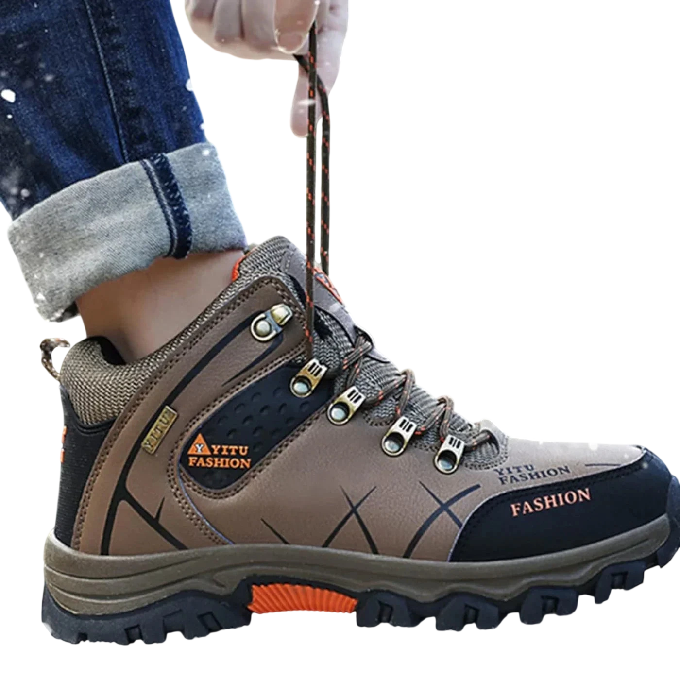 Osoba ubrana w Arkadya Outlet męskie buty wodoodporna konstrukcja ergonomiczna podeszwa z pomarańczowymi akcentami stąpa po śniegu, wiążąc sznurówki. Dżinsy mają mankiety, a ergonomiczne buty otaczają płatki śniegu.