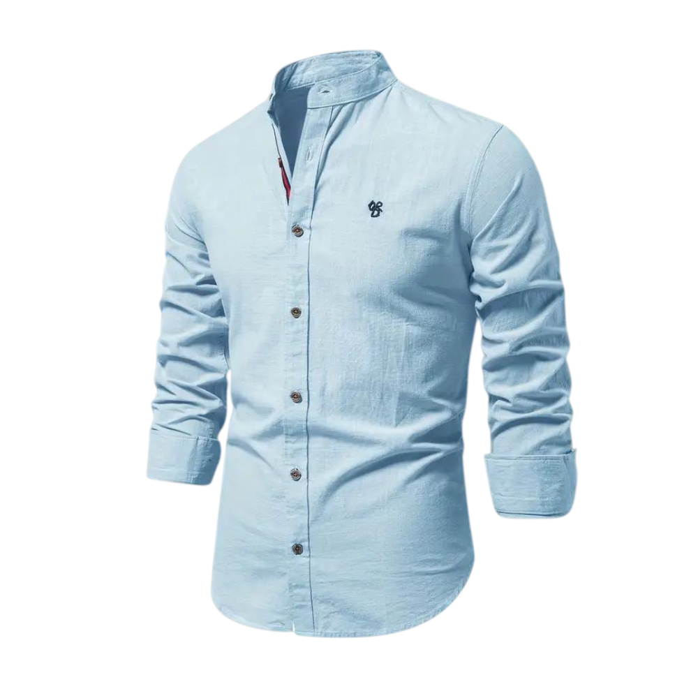 Arkadya Outlet Koszula męska kołnierz stójka długi rękaw krój regularny to jasnoniebieska koszula z zapięciem na guziki z przodu i haftowanym logo, idealna do codziennego użytku, pokazana na rozmytym tle wnętrza.