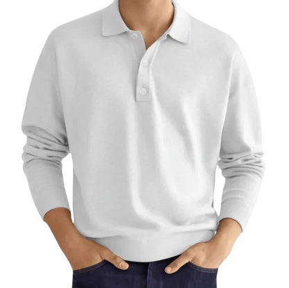 Mężczyzna w koszulce Arkadya Outlet Koszulka polo męska długi rękaw półguziki kołnierz, ręce w przednich kieszeniach ciemnych spodni, stojący na białym tle.