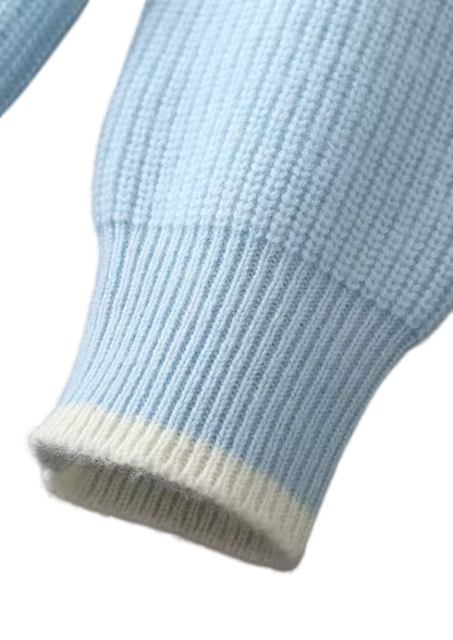 Zbliżenie na rękaw z męskiego dekoltu Arkadya Outlet Sweter okrągły prążkowana dzianina standardowy krój w kolorze jasnoniebieskim, ukazujący jego prążkowaną fakturę i mankiet z białymi krawędziami na gładkim białym tle.