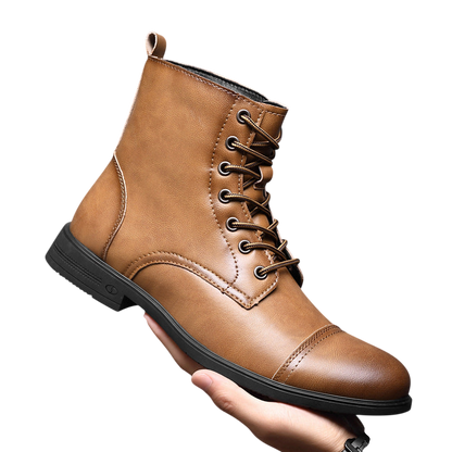 Ręka trzyma Arkadya Outlet Buty męskie wysoka cholewka z wiązaniem pełna wysokość - brązowe skórzane sznurowane buty z zakrytym czubkiem i czarną podeszwą - wyświetlane na jednolitym szarym tle.