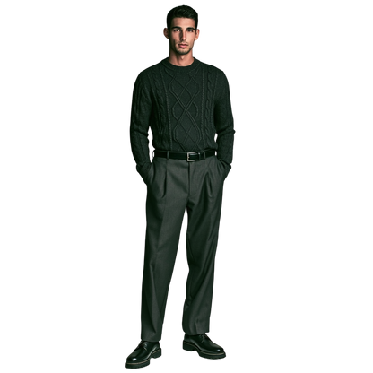 Mężczyzna stoi na prostym tle w męskim dekolcie Arkadya Outlet Sweter okrągły warkoczowy, szarych spodniach i czarnych butach wizytowych, z rękami w kieszeniach.