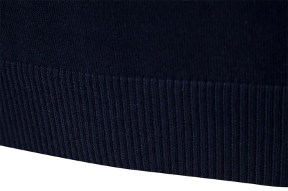 Zbliżenie na granatowy prążkowany materiał na brzegu męskiego półzamka fasonu pulower Arkadya Outlet Sweter, podkreślający jego teksturowany pionowy wzór na neutralnym tle.