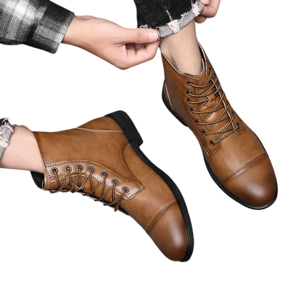 Osoba ubrana w Arkadya Outlet Buty męskie z wysokim sznurowaniem i pełnym wzrostem siedzi na podłodze wyłożonej kafelkami, dopasowując jeden but, mając na sobie podwinięte dżinsy.