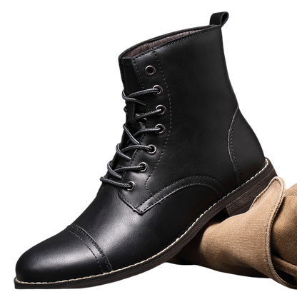 Buty męskie Arkadya Outlet mają czarną skórzaną cholewkę, sznurowaną konstrukcję, zaokrąglony nosek z detalami i białą podeszwę, pokazaną pionowo na kraciastej powierzchni z brązowym materiałem z tyłu.