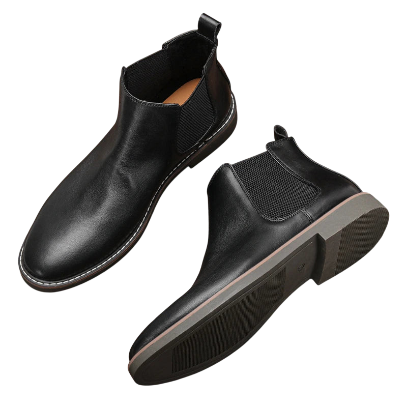 Arkadya Outlet Botki męskie wsuwane sztyblety zimowe zamknięta forma wykonane z czarnej skóry, z elastycznymi panelami, uchwytami z tyłu i gumową podeszwą z brązowym akcentem, prezentowane na białym tle.