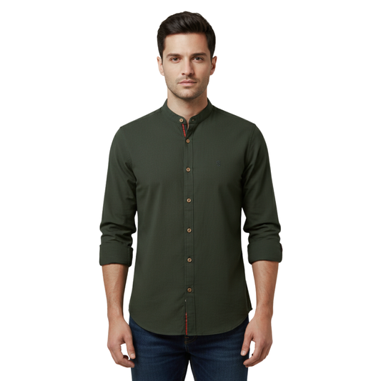 Mężczyzna o krótkich ciemnych włosach, ubrany w kurtkę Arkadya Outlet Koszula męska kołnierz stójka długi rękaw krój regularny w kolorze ciemnozielonym, podwinięte rękawy, ciemne dżinsy, stojący przodem na białym tle.