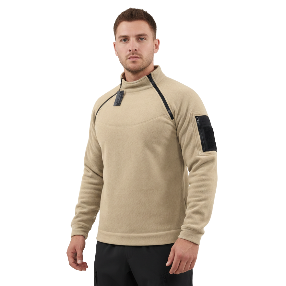 Mężczyzna stoi przodem do prostego białego tła, ubrany w kurtkę Arkadya Outlet Bluza męska polarowa długi rękaw z kieszeniami w kolorze beżowym, z zamkiem błyskawicznym na ramionach i czarną naszywką na lewym rękawie.