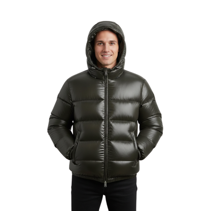 Mężczyzna ubrany w Arkadya Outlet Kurtka Pikowana Męska Krótka Długość Konstrukcja Komorowa z kapturem pozuje z rękami w kieszeniach, uśmiechając się do kamery na jednolitym białym tle.