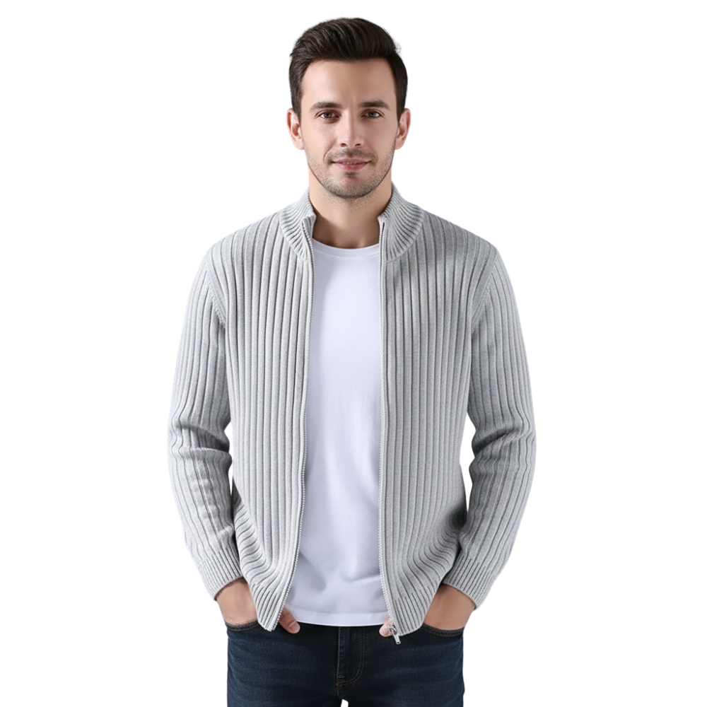 Mężczyzna z krótkimi ciemnymi włosami nosi Arkadya Outlet Kardigan Męski Dzianinowy Prążkowana Faktura Zamek Długi Rękaw na białej koszulce i ciemnych dżinsach, stojąc z rękami w kieszeniach na białym tle.