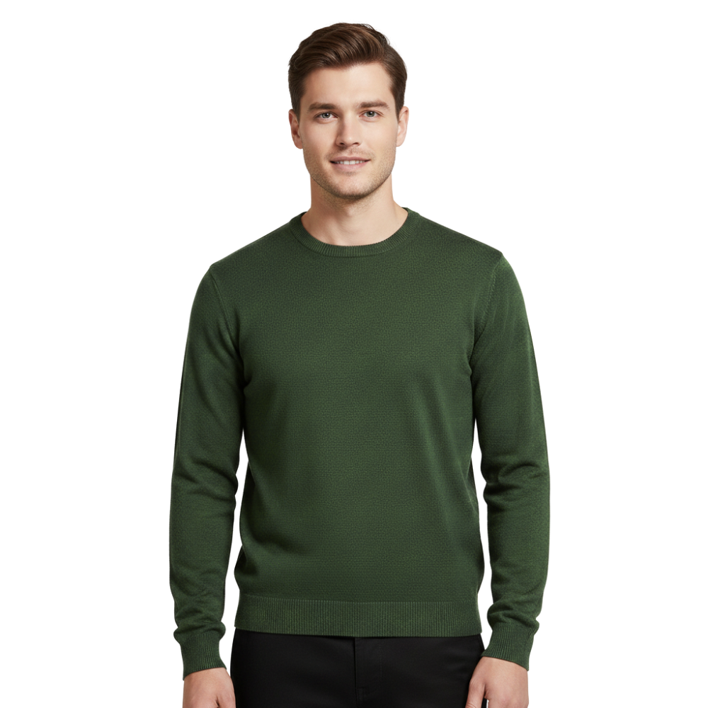 Młody mężczyzna z krótkimi brązowymi włosami stoi uśmiechnięty, ubrany w Arkadya Outlet Sweter dzianinowy męski długi rękaw w kolorze ciemnozielonym z czarnymi spodniami, na prostym białym tle.