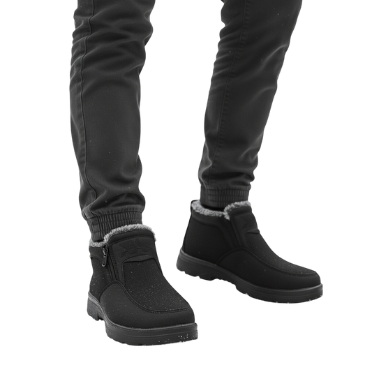 Osoba w ciemnych spodniach nosi Arkadya Outlet Męskie buty wodoodporne antypoślizgowe zimowe obuwie, stojąc na ośnieżonej ziemi z drzewami w tle.