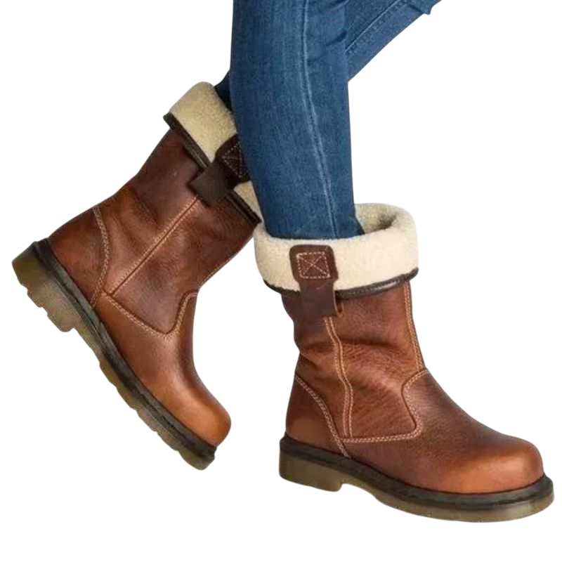 Osoba nosi niebieskie dżinsy i Arkadya Outlet Buty za kostkę męskie wsuwane z okrągłym noskiem i podeszwą, z solidnymi podeszwami i lekką futrzaną podszewką, z wierzchami złożonymi, aby odsłonić przytulne wnętrze na jednolitym tle.