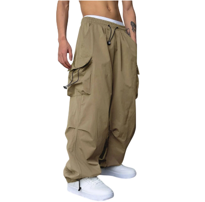 Osoba nosząca cargo Arkadya Outlet Męskie Spodnie (szeroka nogawka, wiele kieszeni) stoi bez koszulki w białych trampkach na tle białej ściany i ciemnej podłogi.