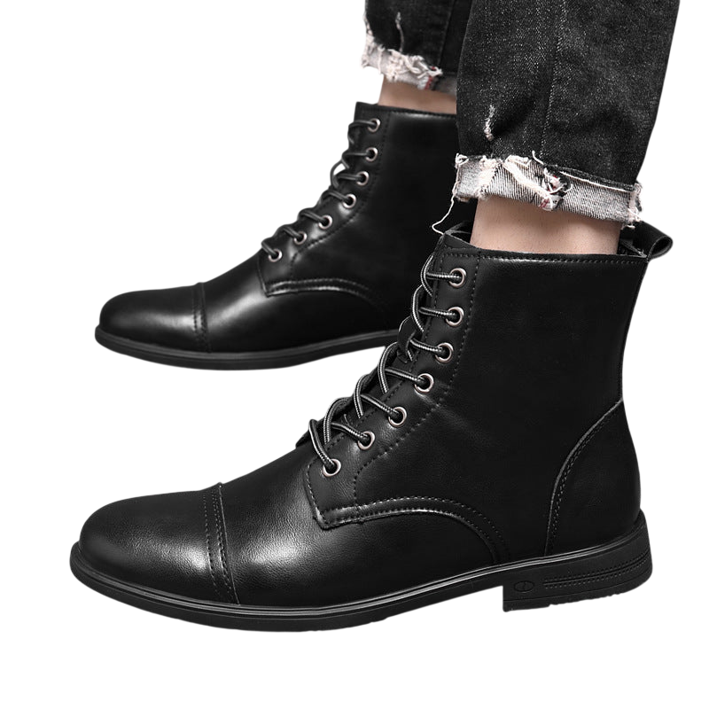 Osoba nosząca Buty męskie Arkadya Outlet z wysokim sznurowanym trzonem i pełną wysokością stoi na podłodze wyłożonej kafelkami, w połączeniu z postrzępionymi dżinsami z mankietami. Buty mają metalowe oczka i widoczne szwy.