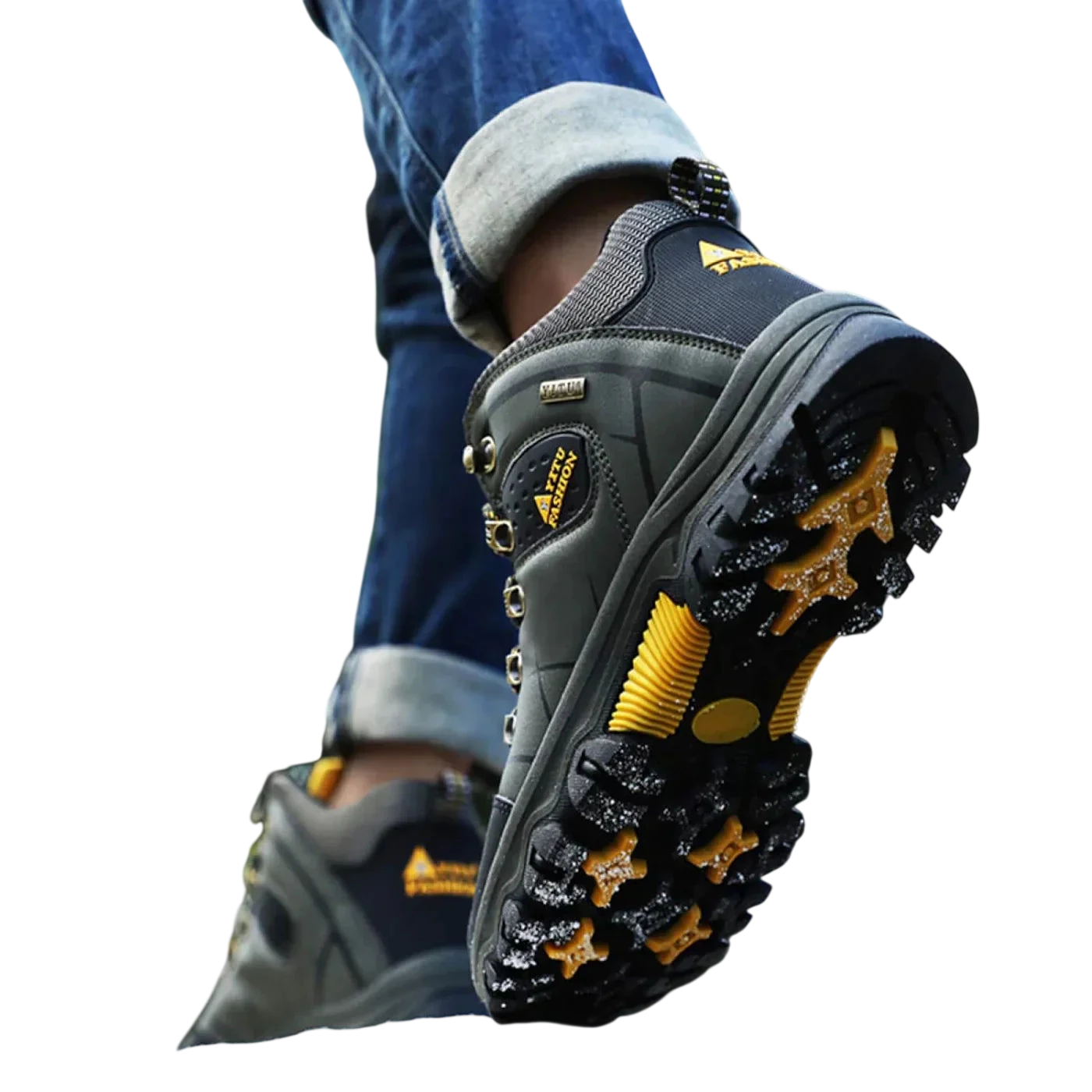 Zbliżenie stopy osoby w Arkadya Outlet Męskie buty wodoodporna konstrukcja ergonomiczna podeszwa z grubym żółto-czarnym bieżnikiem, stąpanie po zaśnieżonej ziemi na zewnątrz. W tle widoczne są podwinięte dżinsy i rozmyte drzewa.