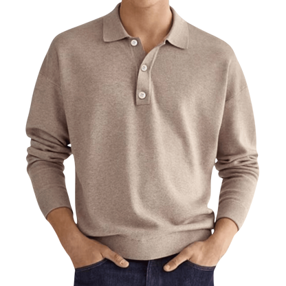 Mężczyzna w ciemnych dżinsach nosi koszulkę Arkadya Outlet Koszulka polo męska długi rękaw półguziki kołnierz wzór, stojąc z rękami w kieszeniach na jednolitym tle.