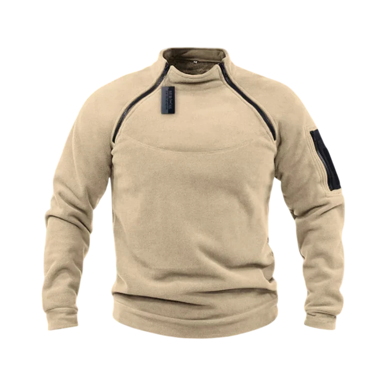 Beżowa bluza męska polarowa Arkadya Outlet z długim rękawem, wysokim kołnierzem, zamkami na froncie i ramieniu oraz kieszenią na lewym rękawie, prezentowana na tle rozmytych gór.