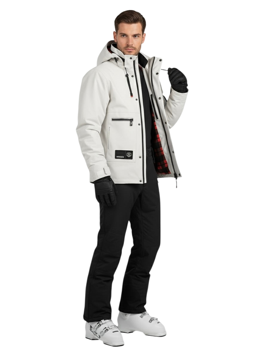Mężczyzna ubrany w kurtkę Zewnętrzna Męska Wodoodporna z zapięciem na zamek, czarne rękawiczki, czarne spodnie i białe buty narciarskie stoi przodem do kierunku jazdy. Kurtka jest częściowo rozpięta, aby pokazać czerwono-czarną podszewkę w kratę.
