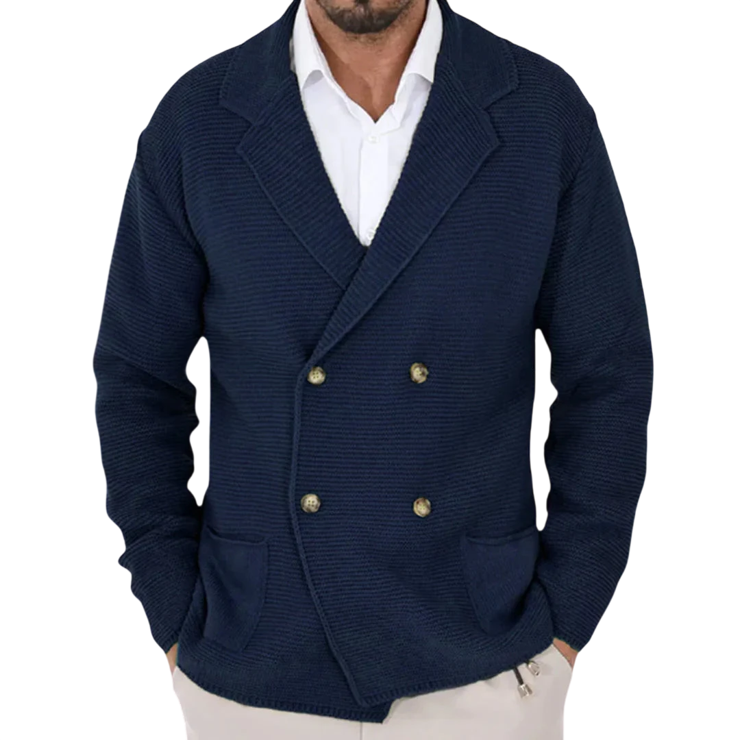 Mężczyzna nosi Arkadya Outlet Kardigan męski dwurzędowy krój typu marynarka z kołnierzem ze złotymi guzikami na białej koszuli, stojąc w pomieszczeniu na tle rozmytych stojaków z ubraniami.