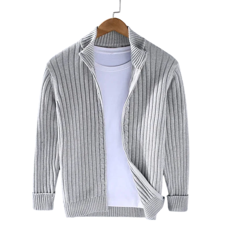 Kardigan Męski Dzianinowy Prążkowana Faktura Zamek Długi Rękaw marki Arkadya Outlet prezentowany jest na drewnianym wieszaku na białym T-shircie na szarym tle. Jasnoszary kardigan ma długie rękawy, otwarty przód i luźny krój - idealny do noszenia na co dzień.