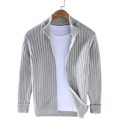 Kardigan Męski Dzianinowy Prążkowana Faktura Zamek Długi Rękaw marki Arkadya Outlet prezentowany jest na drewnianym wieszaku na białym T-shircie na szarym tle. Jasnoszary kardigan ma długie rękawy, otwarty przód i luźny krój - idealny do noszenia na co dzień.
