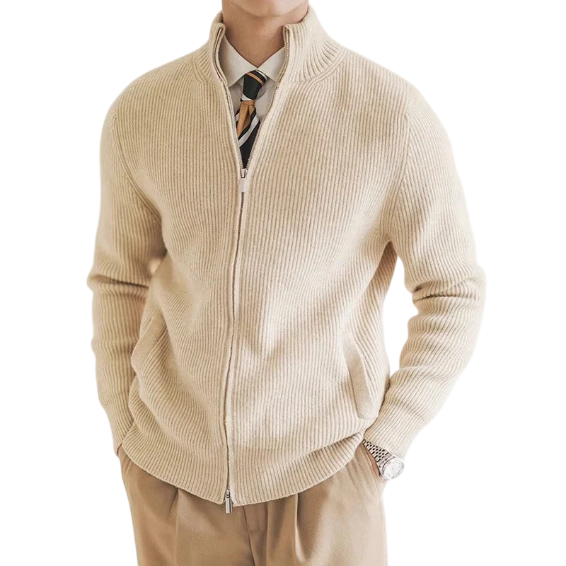 Mężczyzna nosi Arkadya Outlet Kardigan męski zapinany na zamek błyskawiczny dopasowany krój w kolorze beżowym na białej koszuli i wzorzystym krawacie, z brązowymi spodniami i zegarkiem na rękę, ręce w kieszeniach.