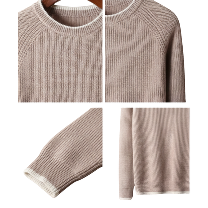 Zbliżenie na Arkadya Outlet Sweter męski dekolt okrągły prążkowana dzianina standardowy krój w kolorze beżowym z białymi wykończeniami na kołnierzu, mankietach i rąbku - prezentowany na drewnianym wieszaku i ułożony płasko, aby podkreślić fakturę i detale.