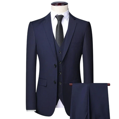 Arkadya Outlet Zestaw Garniturowy Męski Trzyczęściowy Z Marynarką I Kamizelką w kolorze ciemnogranatowym jest prezentowany na manekinie w białej koszuli i czarnym krawacie, na jednolitym jasnoszarym tle.