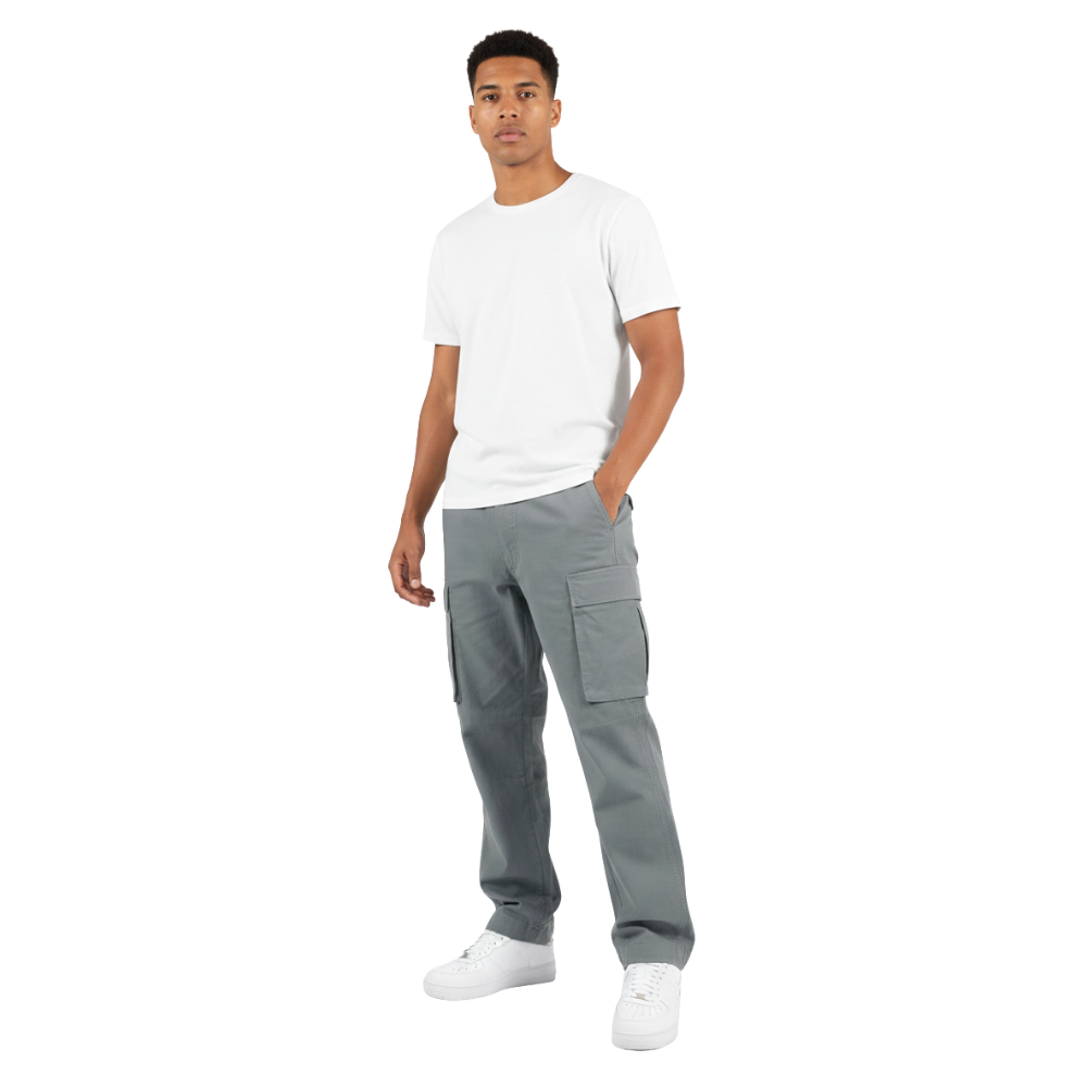 Mężczyzna stoi przodem z jedną ręką w kieszeni, ubrany w zwykłą białą koszulkę, Arkadya Outlet Spodnie cargo męskie prosta nogawka z wieloma kieszeniami i białe trampki na białym tle.