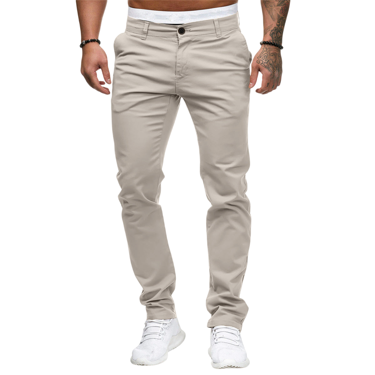 Na szarym tle stoi mężczyzna ubrany w Arkadya Outlet Męskie spodnie w dopasowanym kroju z prostą nogawką, białą koszulę, białe sneakersy i czarne bransoletki. Twarz nie jest widoczna.