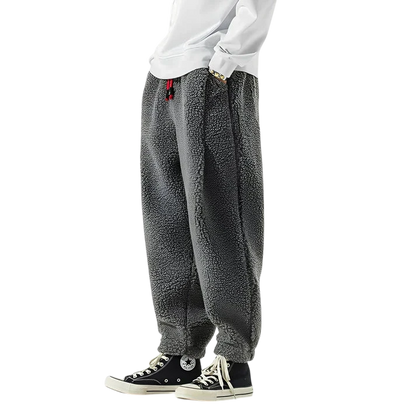 Osoba ma na sobie Arkadya Outlet Spodnie Męskie Luźny Krój Elastyczny Pas Do Domu I Wypoczynku, białą bluzę i czarne wysokie trampki Converse. Tylko dolna część ciała jest widoczna na białym tle.