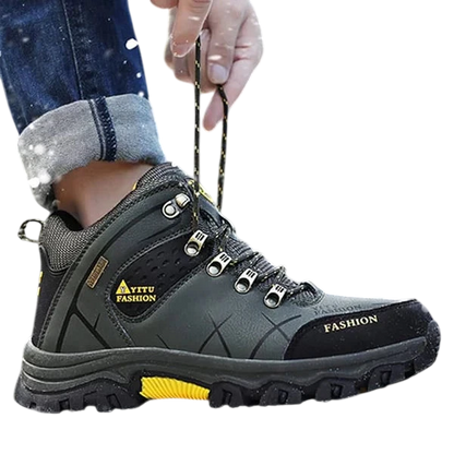 Osoba ubrana w ciemnozielone Arkadya Outlet męskie buty wodoodporna konstrukcja ergonomiczna podeszwa z żółtymi akcentami i napisem "FASHION" z boku stoi na zaśnieżonej ziemi, regulując sznurówki, gdy pada śnieg, a drzewa rozmywają się w tle.