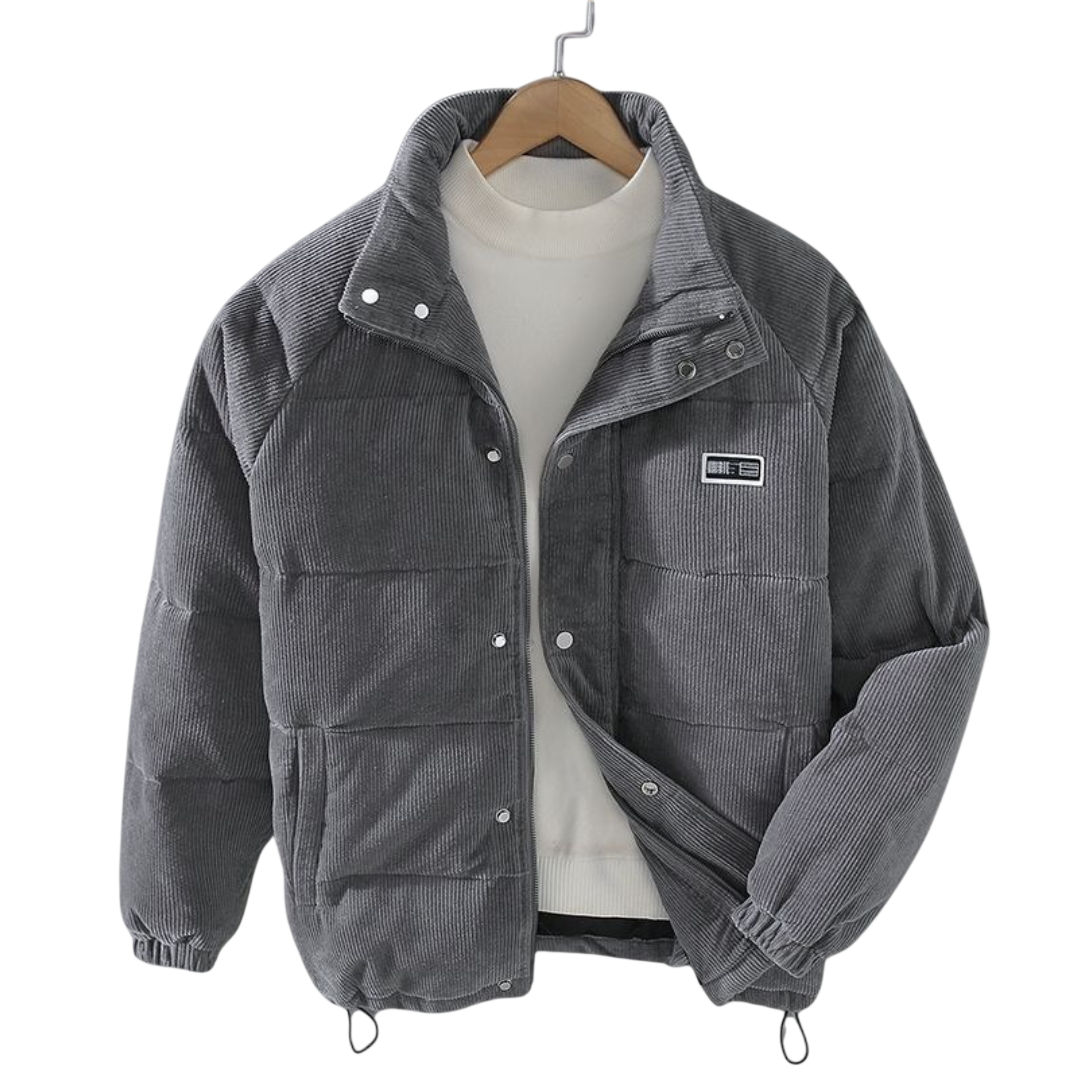 Arkadya Outlet Kurtka zimowa męska strukturalny krój z czystymi liniami, szara sztruksowa kurtka z guzikami zatrzaskowymi, wysokim kołnierzem i naszywką na piersi, jest prezentowana na wieszaku na białym golfie na jednolitym tle.