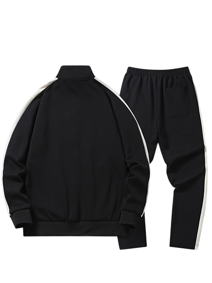 Arkadya Outlet Komplet dresowy męski dwuczęściowy codzienny strój to czarny zestaw z białymi paskami po bokach, w tym bluzka z długim rękawem zapinana na suwak i dopasowane spodnie z elastycznym pasem i tylną kieszenią, pokazane na białym tle.