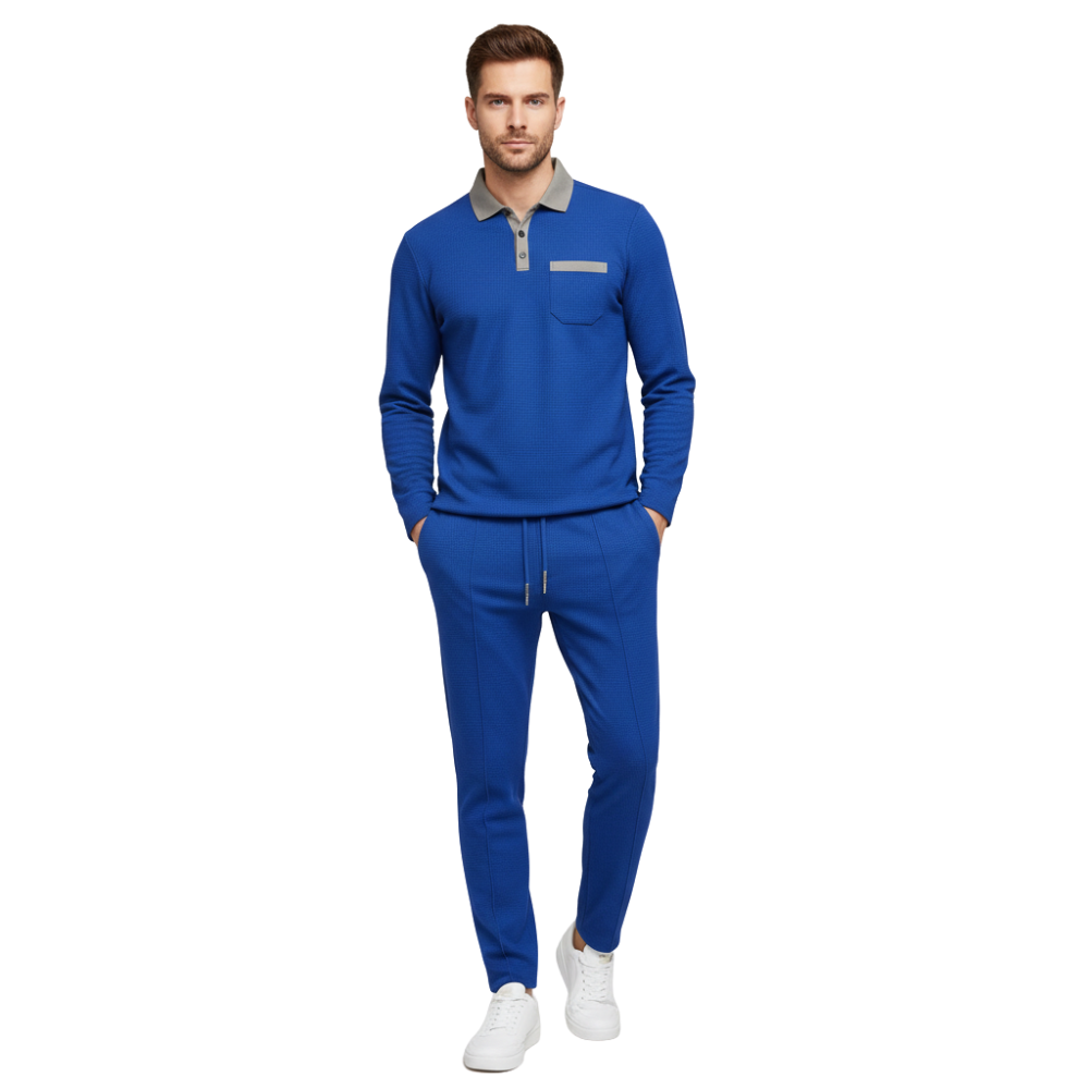 Mężczyzna stoi przodem do kierunku jazdy w Arkadya Outlet Komplet dresowy męski dwuczęściowy długi rękaw użytkowy zestaw-niebieska bluza i dopasowane spodnie dresowe na szarej koszuli, ręce w kieszeniach, w białych tenisówkach na białym tle.