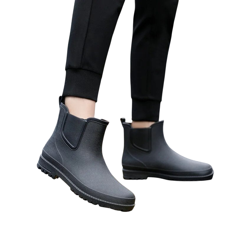 Osoba ubrana w Arkadya Outlet Buty Chelsea męskie zimowe wsuwane antypoślizgowe i czarne spodnie stoi na jasnoszarym tle.