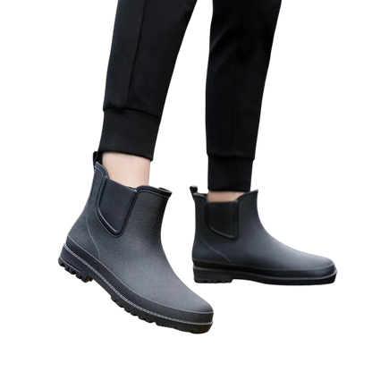 Osoba ubrana w Arkadya Outlet Buty Chelsea męskie zimowe wsuwane antypoślizgowe i czarne spodnie stoi na jasnoszarym tle.