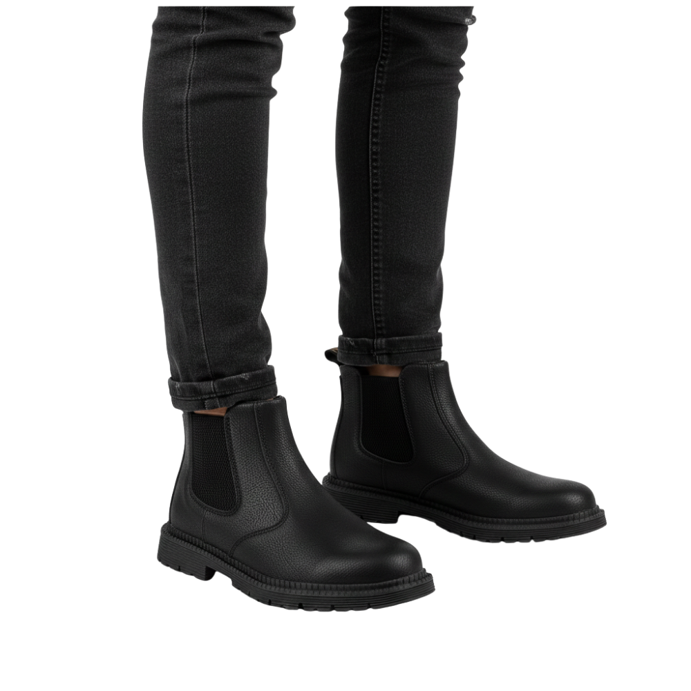 Na białym tle stoi osoba ubrana w czarne jeansy skinny i buty Arkadya Outlet Buty Robocze Męskie z zabudowanym noskiem i trwałą konstrukcją, z grubymi, chropowatymi podeszwami.