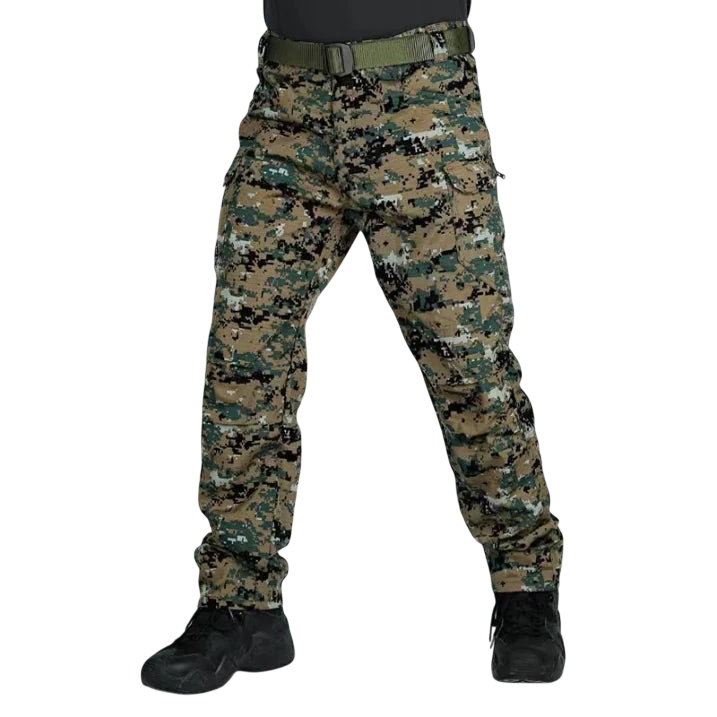 Osoba stoi z rozstawionymi nogami, ubrana w spodnie Arkadya Outlet cargo męskie krój slim z wieloma kieszeniami użytkowymi w kamuflażu cyfrowym, zielony pasek, czarne buty i ciemną koszulę. Zdjęcie jest przycięte powyżej talii na jednolitym jasnoszarym tle.