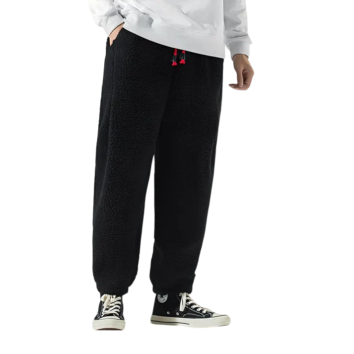 Osoba w Arkadia Outlet Spodnie Męskie Luźny Krój Elastyczny Pas Do Domu I Wypoczynku, z czerwonymi ściągaczami, białą bluzą i czarnymi high-topami z białymi podeszwami stoi na białym tle.