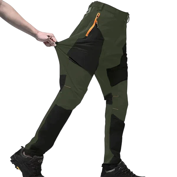 Osoba rozciąga bok swoich zielono-czarnych Spodnie Terenowe Męskie Wodoodporne Wiatroszczelne Regulowane z Outletu Arkadya, podkreślając elastyczny materiał - idealne spodnie outdoorowe, noszone z butami turystycznymi na białym tle.
