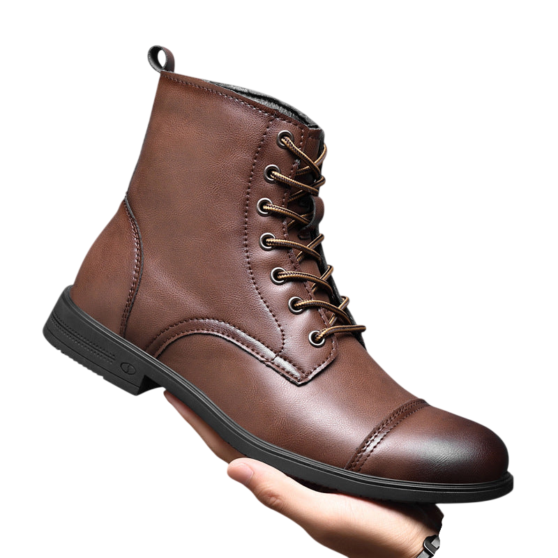 Osoba trzyma buty męskie Arkadya Outlet z pełną wysokością cholewki i wiązaniami, w brązowym kolorze ze złotymi oczkami i czarną podeszwą na tle szarym.