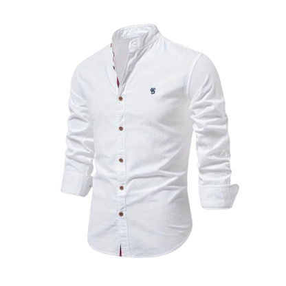 Arkadya Outlet Koszula męska kołnierz stójka długi rękaw krój regularny, biała z brązowymi guzikami i małym haftowanym logo na piersi, jest idealna do noszenia na co dzień i prezentowana na rozmytym tle wnętrza.