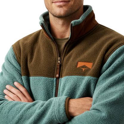 Mężczyzna z założonymi rękami nosi kurtkę Arkadya Outlet Kurtka Męska Prosty Krój Lekka Odzież Wierzchnia Z Długim Rękawem w kolorze turkusowym i brązowym polarem, z zapinanym na zamek kołnierzem, naszywanym logo na piersi i uniwersalnym designem. Jego twarz jest częściowo widoczna na jednolitym tle.