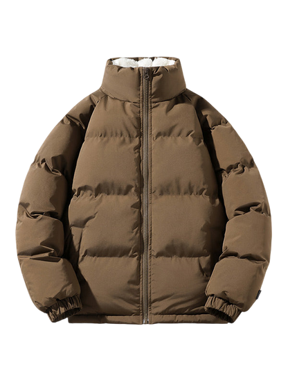 Arkadya Outlet Kurtka Męska Pikowana Konstrukcja z przymocowanym kapturem to brązowa kurtka zimowa w stylu puchowym z wysokim kołnierzem, zamkiem błyskawicznym z przodu i elastycznymi mankietami, pokazana na jednolitym jasnoszarym tle.