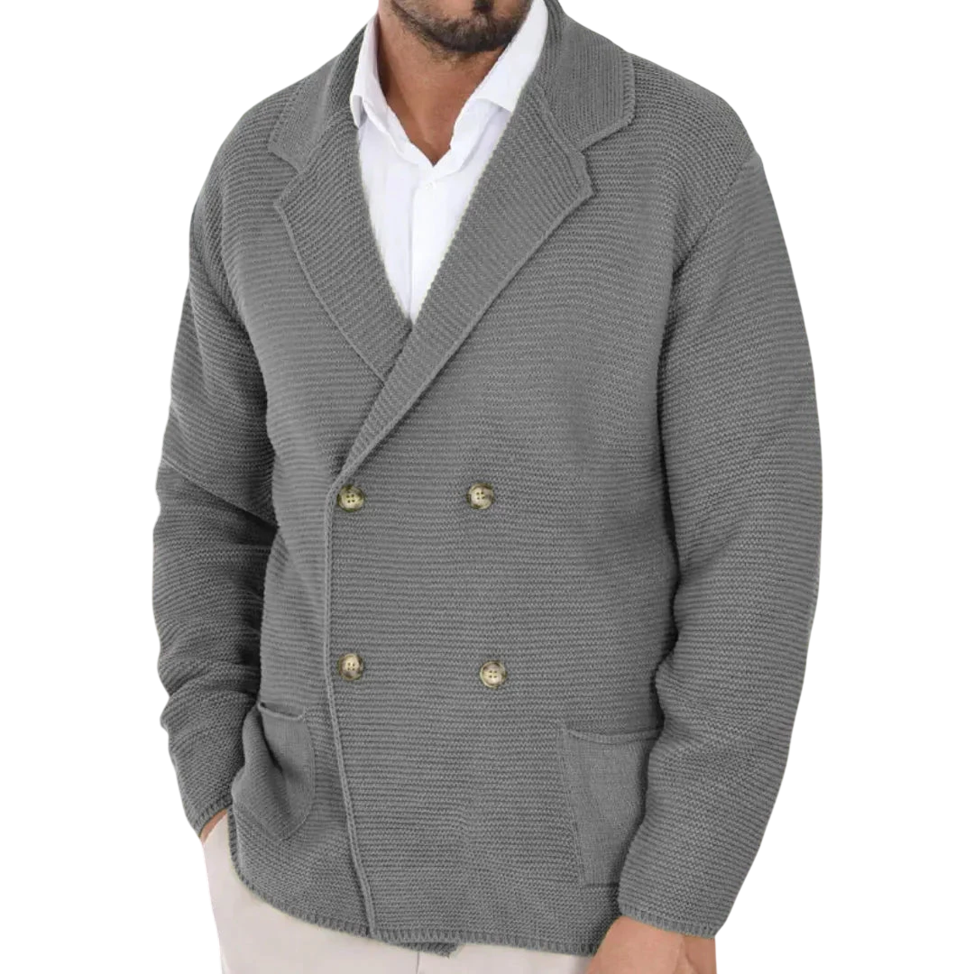 Mężczyzna w Arkadia Outlet Kardigan męski dwurzędowy krój typu marynarka z kołnierzem ze złotymi guzikami na białej koszuli stoi w nowoczesnym, delikatnie rozmytym sklepie odzieżowym.