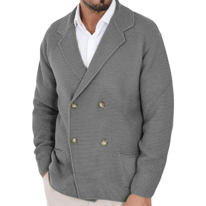 Mężczyzna w Arkadia Outlet Kardigan męski dwurzędowy krój typu marynarka z kołnierzem ze złotymi guzikami na białej koszuli stoi w nowoczesnym, delikatnie rozmytym sklepie odzieżowym.