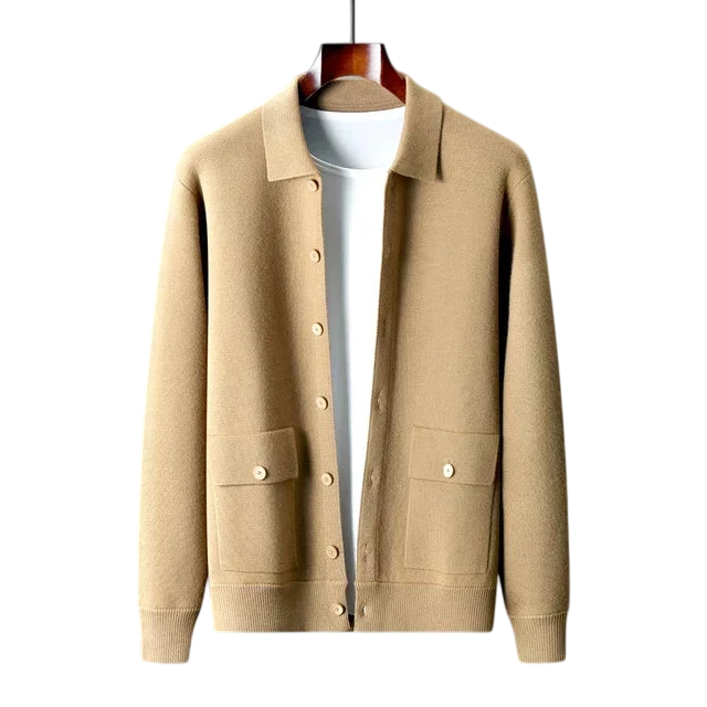 Kardigan męski zapinany na guziki z kołnierzem i kieszeniami Arkadya Outlet w beżowym kolorze prezentowany jest na wieszaku na białej koszuli, na tle gładkiej szarej ściany.